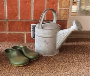 Watering can and gardening shoes on the porch