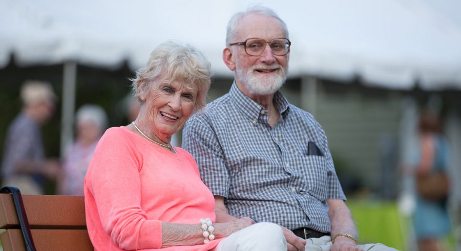 Two seniors smiling on a bench
