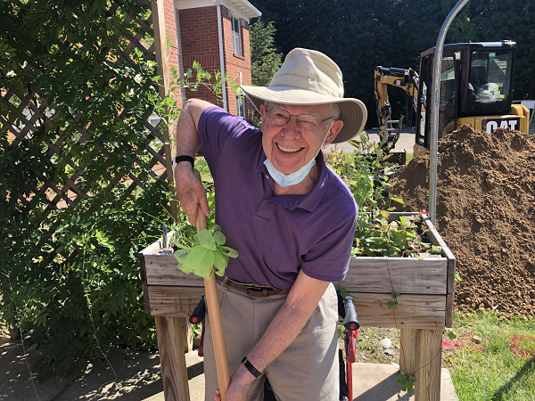 Resident and member of The Highlands Resident Council smiling with shovel, ready to dig