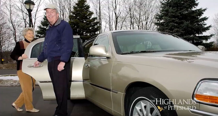 Two seniors outside a car
