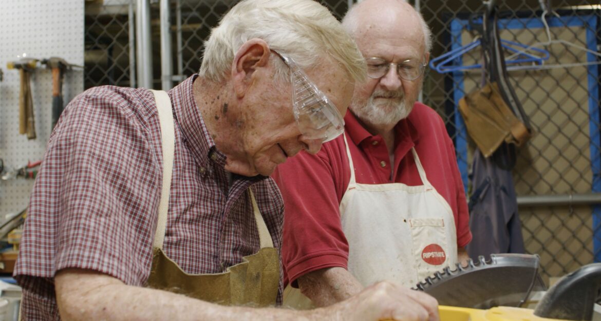 Two resident woodworkers using the saw in the shop on The Highlands at Pittsford campus