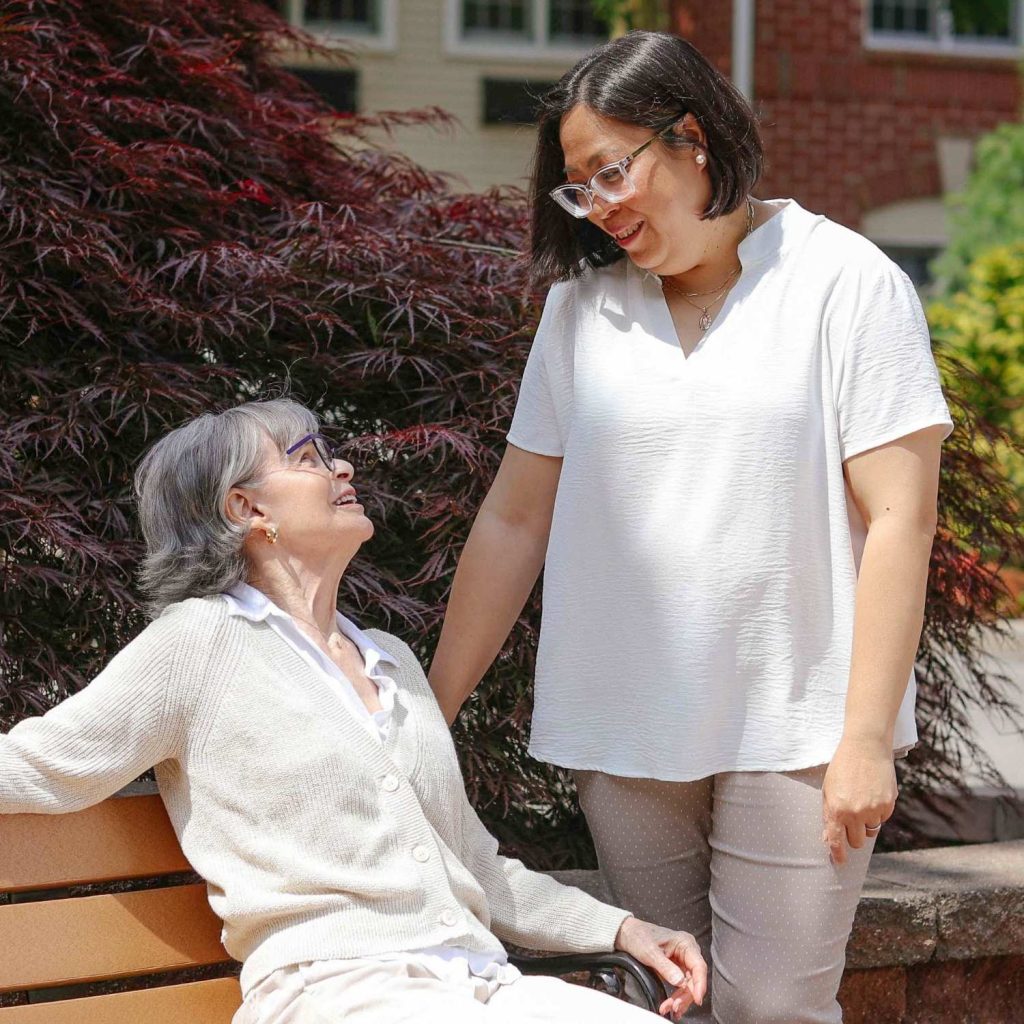 A caregiver talking with a Laurelwood resident in the garden 